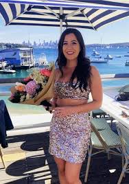 Lauren smiling with flowers by the water